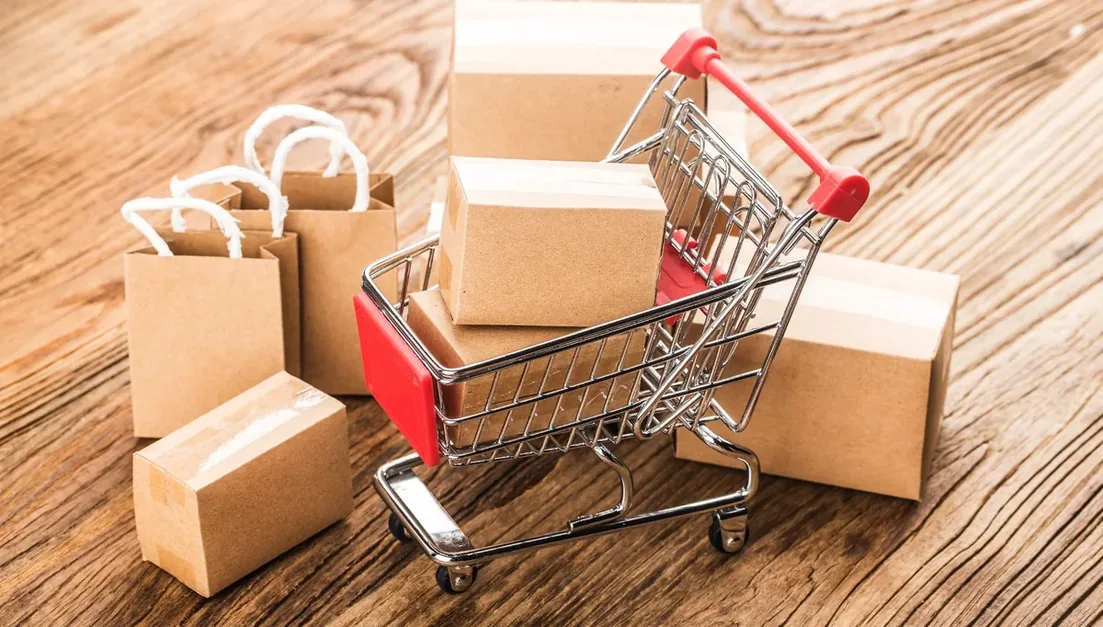 Carrinho de compras em miniatura com caixas de papelão sobre mesa